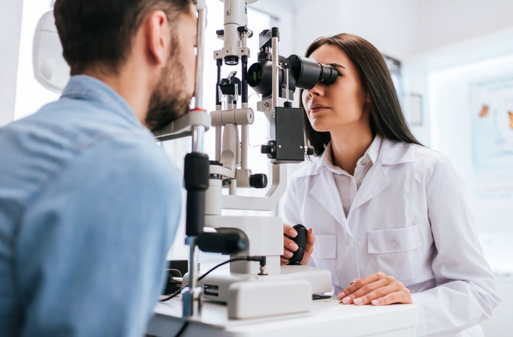 A female optometrist looking at a male patient's eyes with a slit lamp