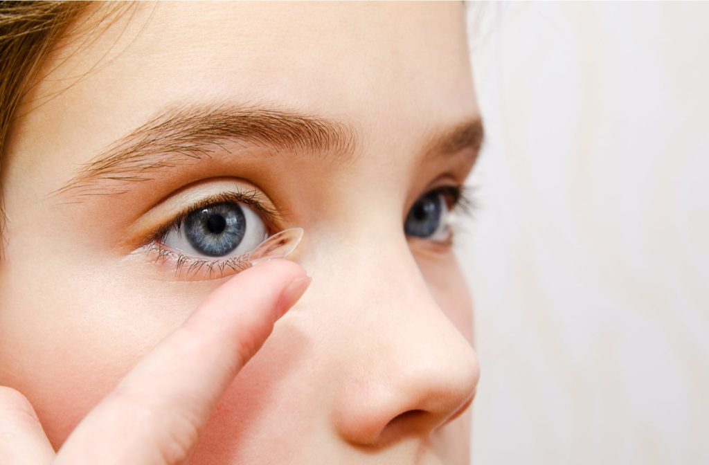 A young girl putting a contact lens in her right eye