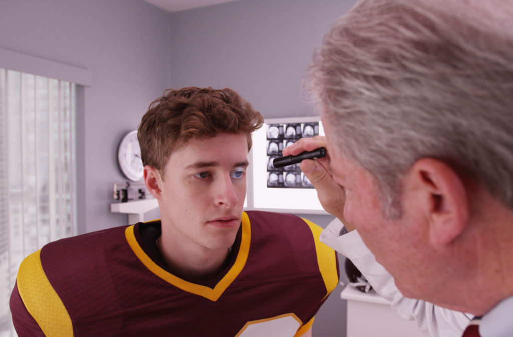 A male athlete with eye trauma is being examined by a doctor.