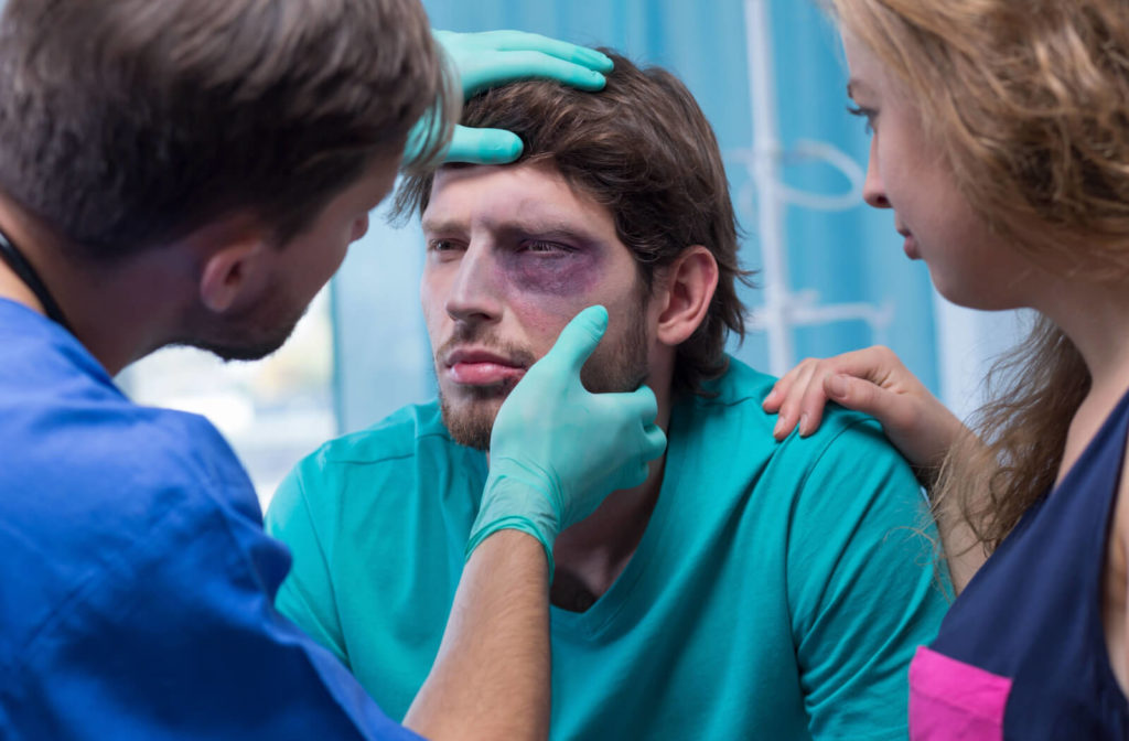 A male doctor is examining a male patient with a black eye in the emergency room.