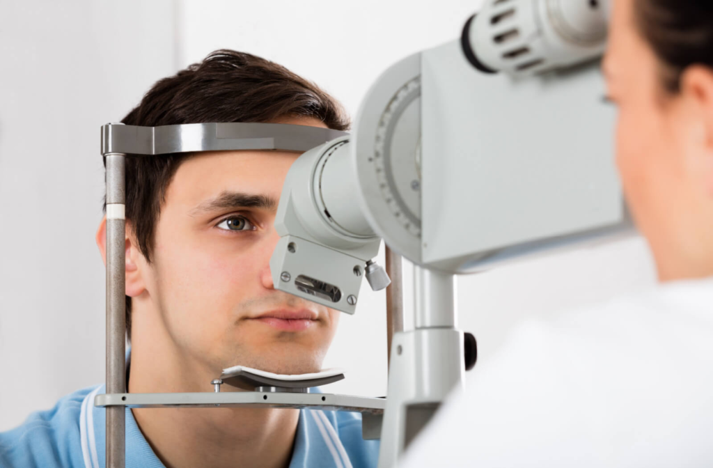 A man sitting in an optometrist office looking into a machine that tests his vision.