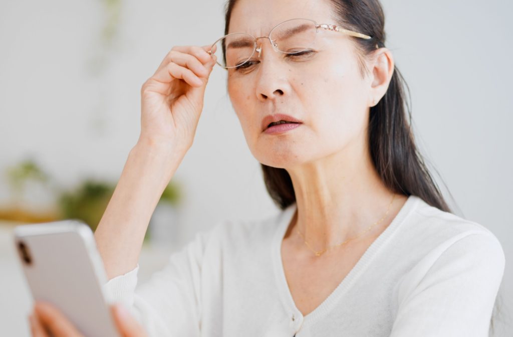 An older woman struggles to read her phone.