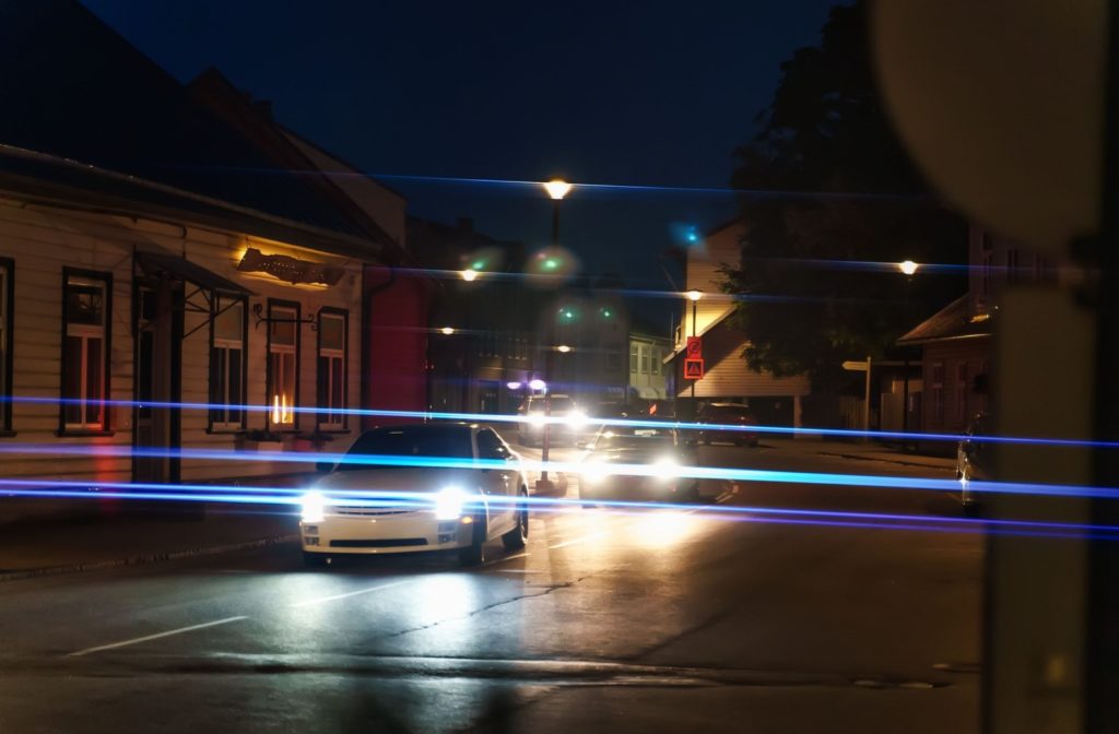 Cars on a street at night with glaring headlights.