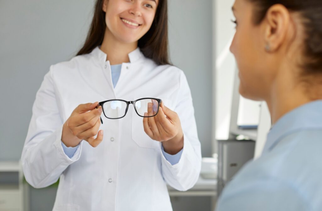 An eye doctor showing a patient a pair of Neurolens glasses to help address eye misalignment.