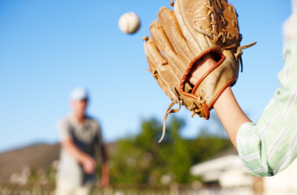 A close up of a baseball glove, showing a person catching a baseball using their visual motor skills.