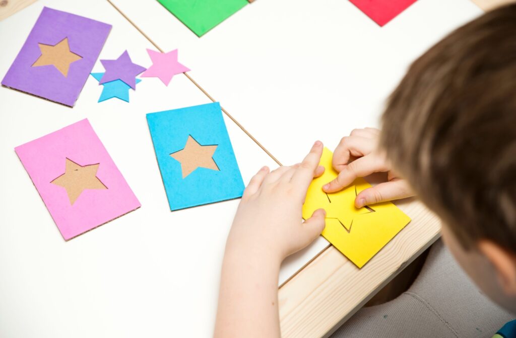 A child matching colored star puzzle pieces to the correct puzzle, demonstrating their visual motor skills.